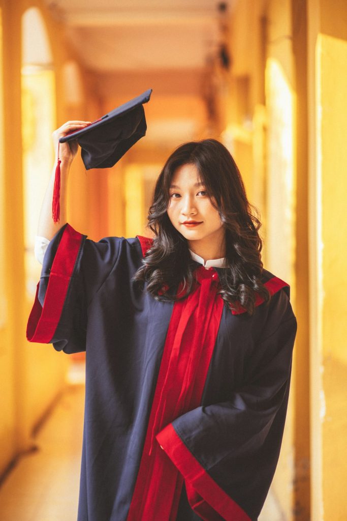 a-woman-in-a-graduation-gown-holding-her-cap-in-the-air-f8lkouwgrrq